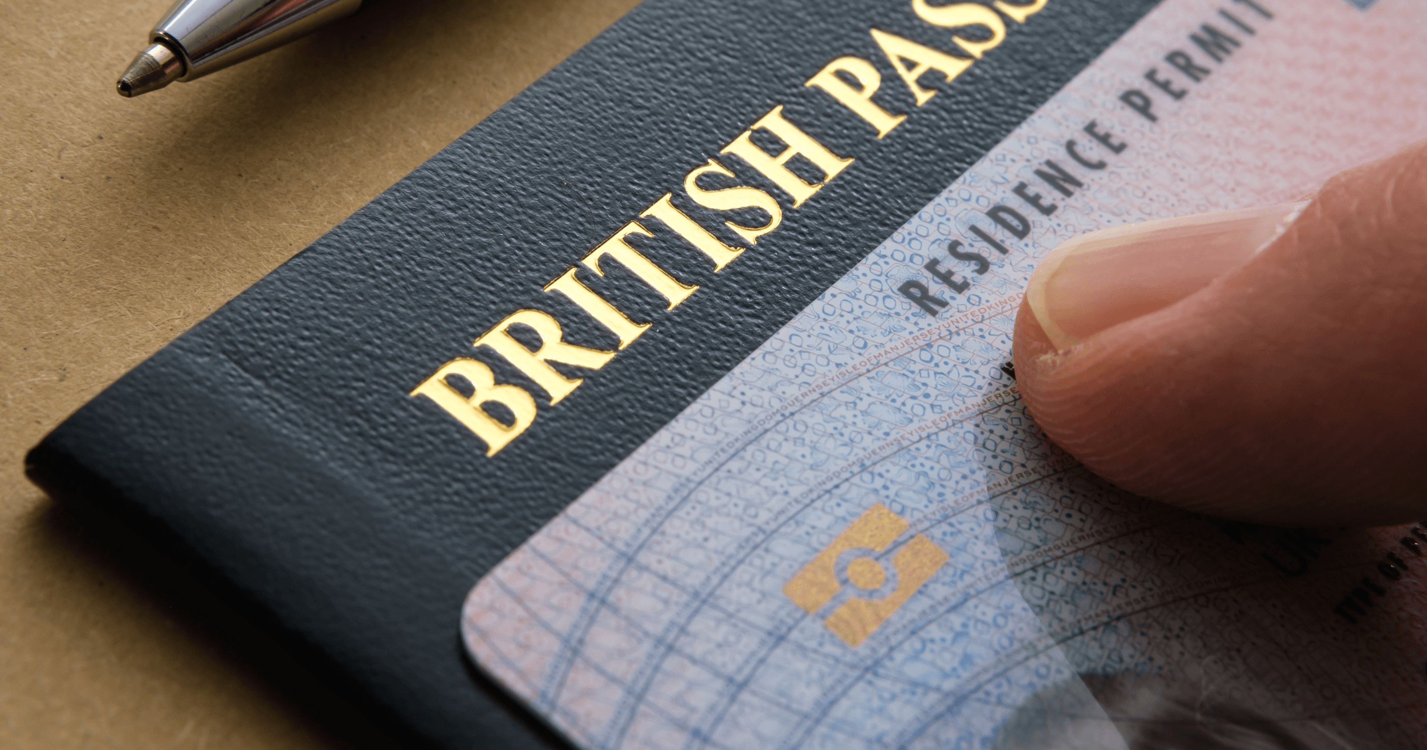 Finger pointing at biometric residence permit card placed on top of British passport